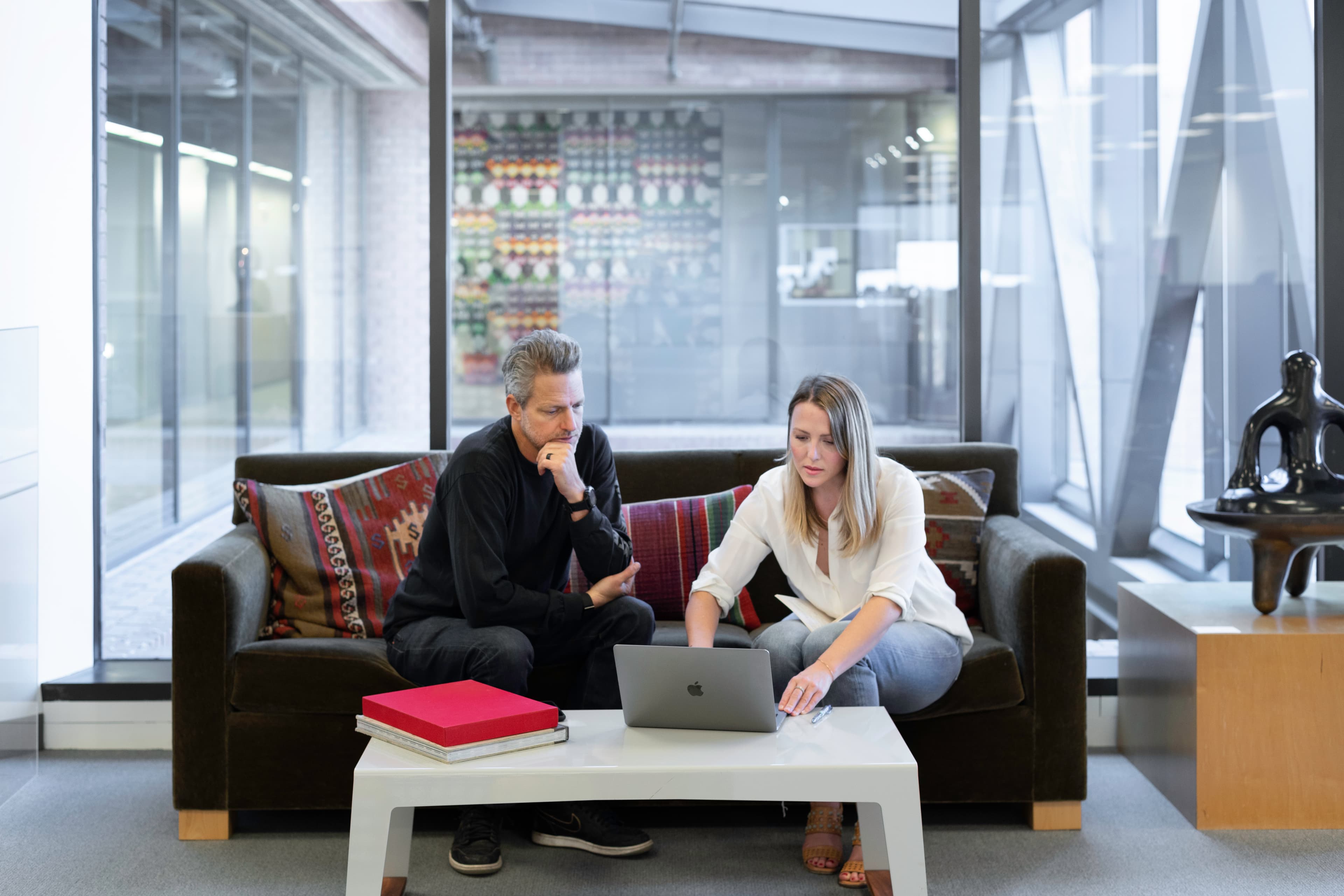 Two people sitting on a couch looking at a laptop