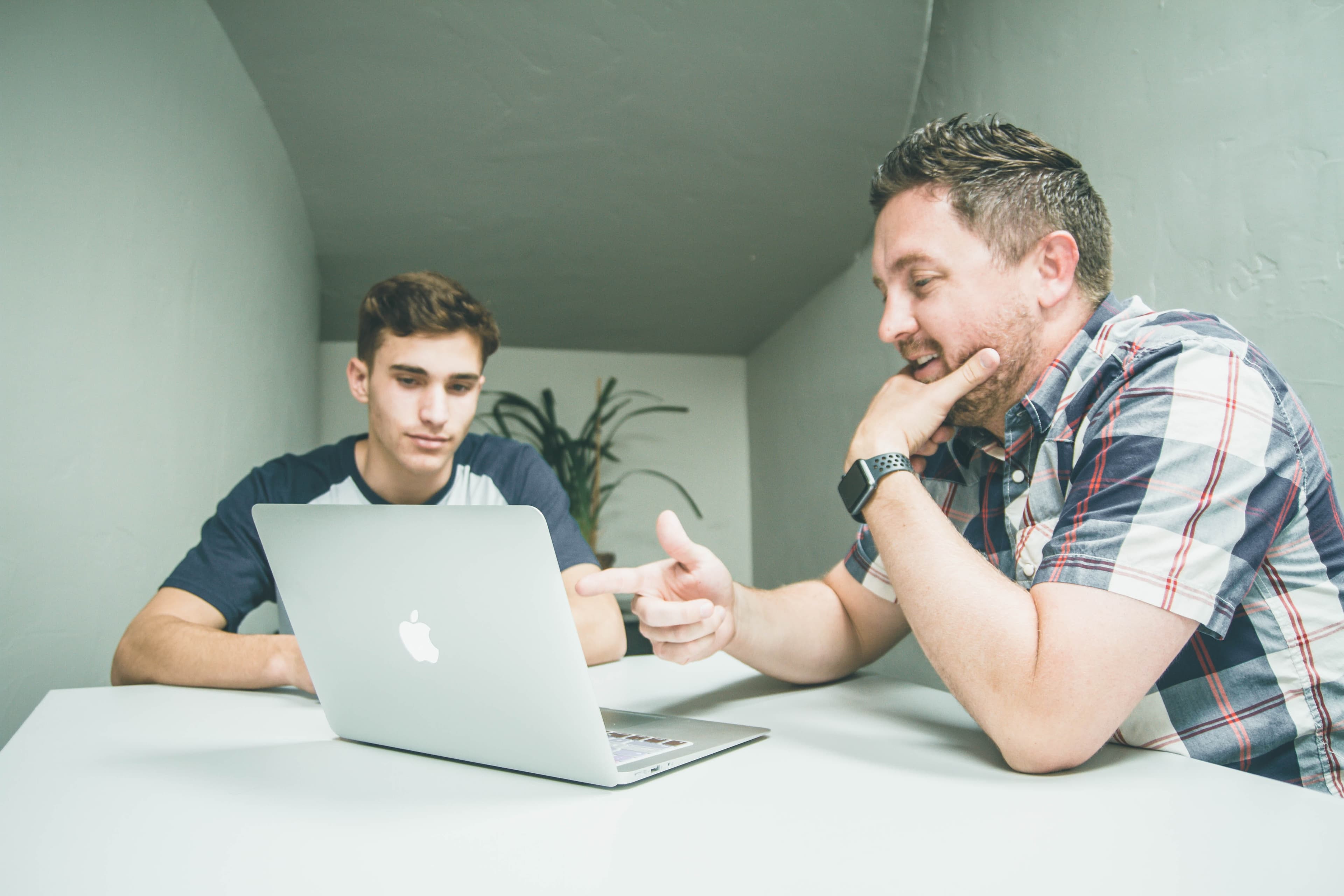 Two men at a conference table working at a laptop
